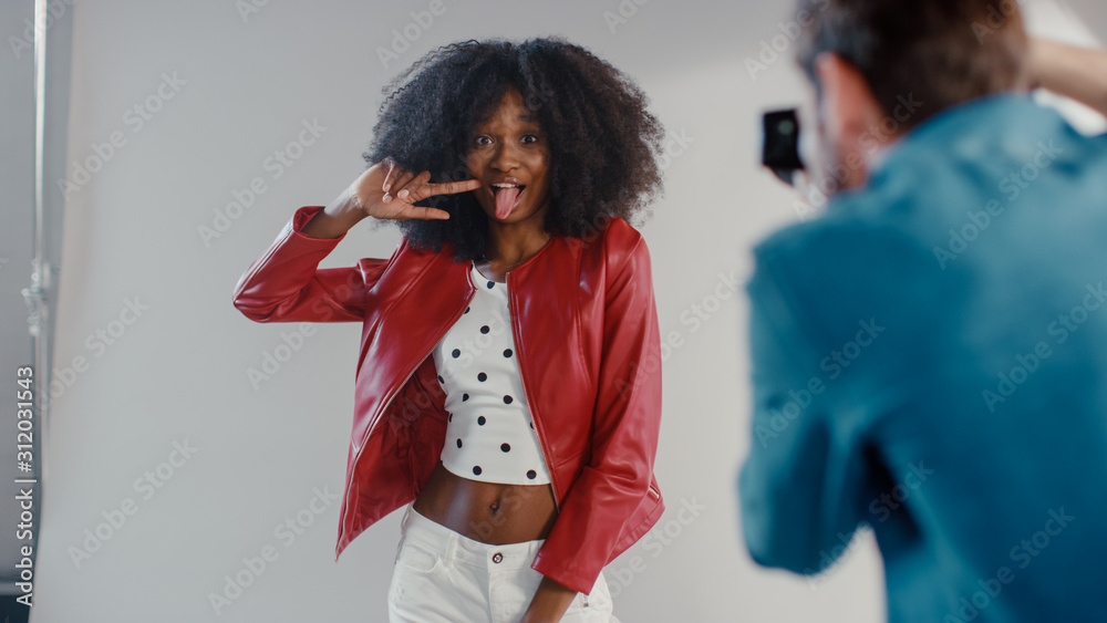 留着浓密卷发的黑人女孩为时尚杂志拍照，用桃子吐舌头