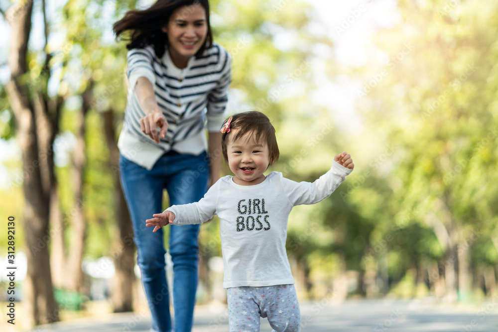 年轻可爱快乐的亚洲小女孩和妈妈在公园里跑步。妈妈在旁边照顾女儿