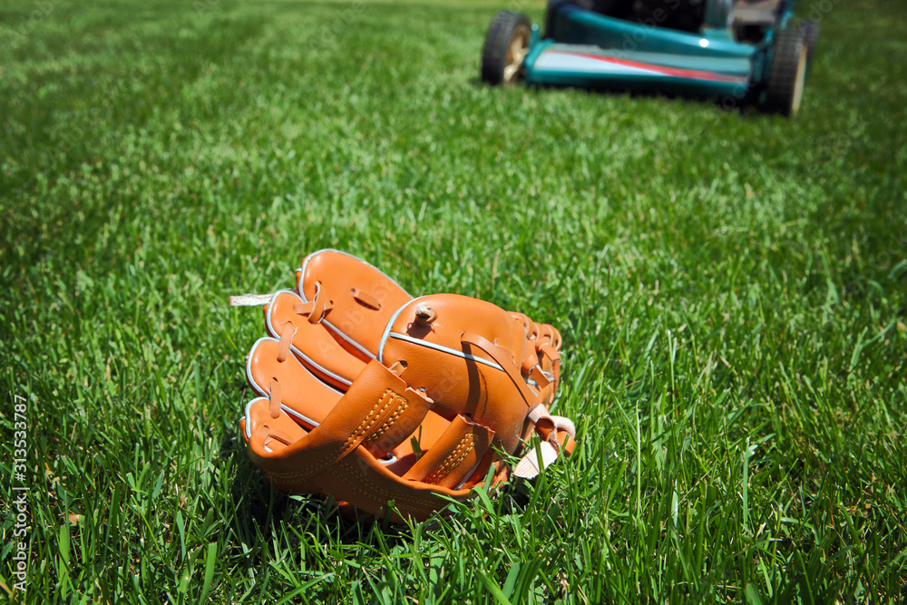 后院的割草机即将碾过躺在草地上的棒球手套