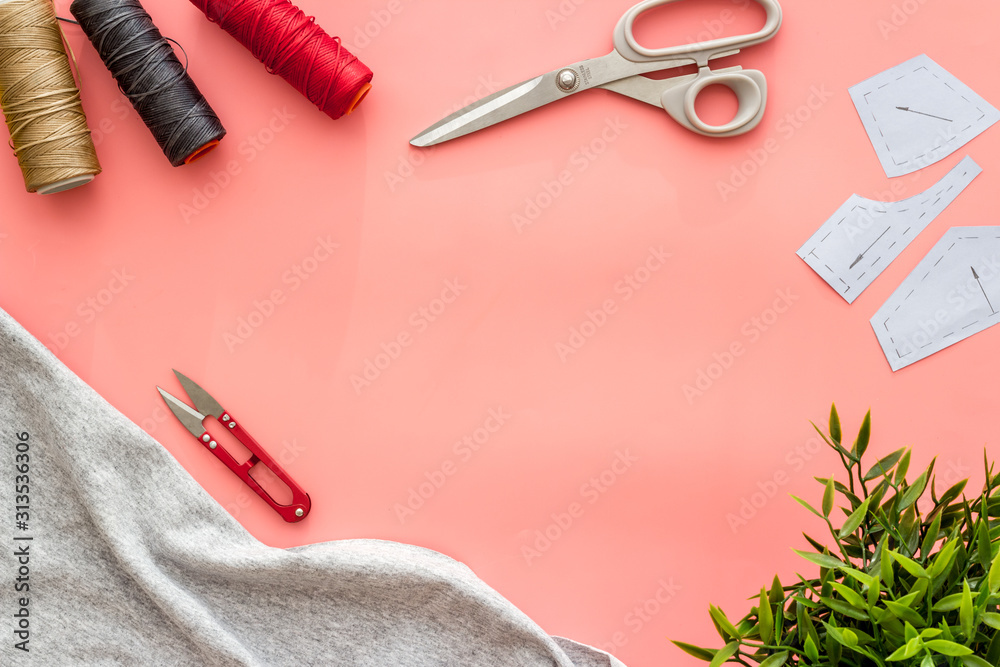 缝纫车间。粉色背景上的纺织品、图案、剪刀、线自上而下的复制空间