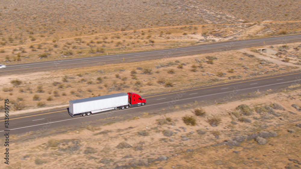 空中飞行：一辆红色货运卡车在犹他州沙漠上空长途行驶。