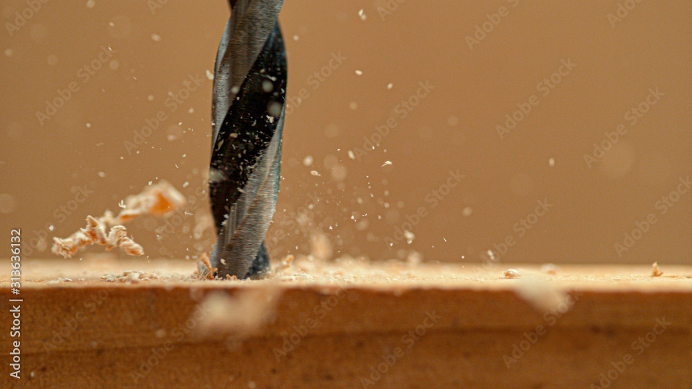 MACRO：当杂工在工件上钻孔时，木屑从木板上飞了下来。