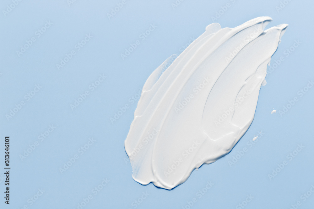 白色化妆品奶油乳液保湿霜在淡蓝色上涂抹。卫生，护肤品奶油色特克斯