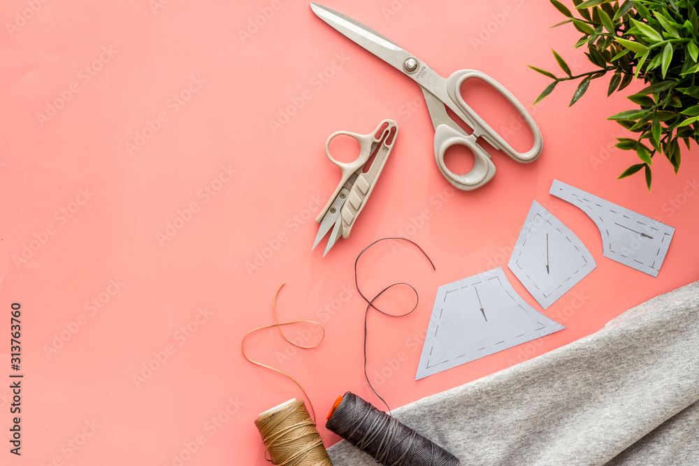 缝纫车间。纺织品、图案、剪刀、粉色背景上的线自上而下的复制空间
