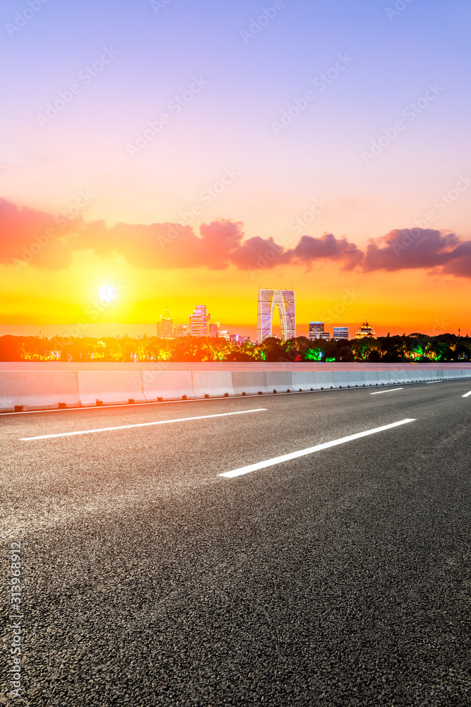 空荡荡的柏油公路和日落时天空色彩斑斓的苏州城市天际线。