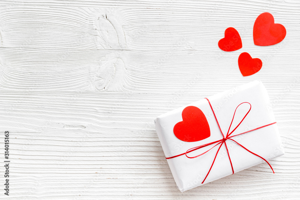 Valentines Day gift. Present box near paper hearts on white wooden background top-down copy space