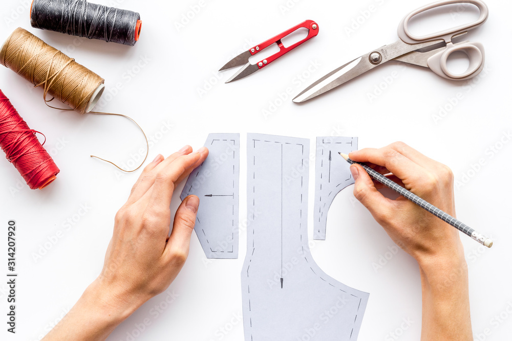 裁缝工作。妇女手工在白色背景上自上而下绘制衣服图案