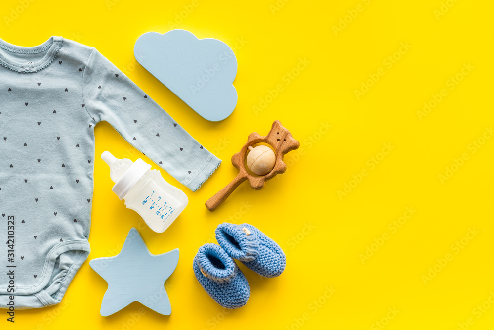 Baby background - blue color. Clothes and accessories for newborn boy on yellow table top-down frame
