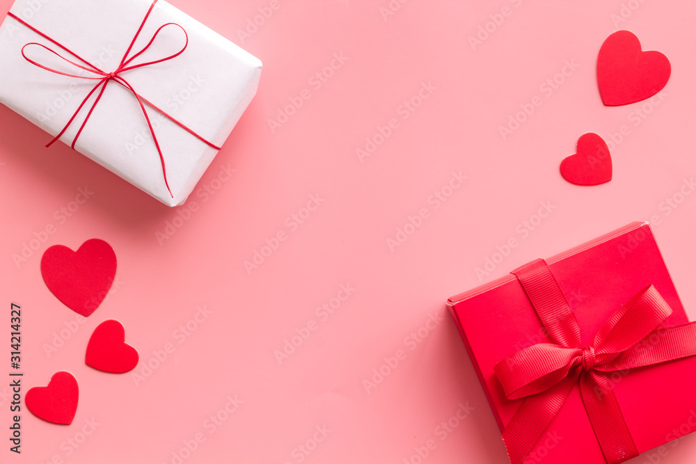 Present to a lover on Valentines Day. Gift boxes near paper hearts on pink background top-down fram