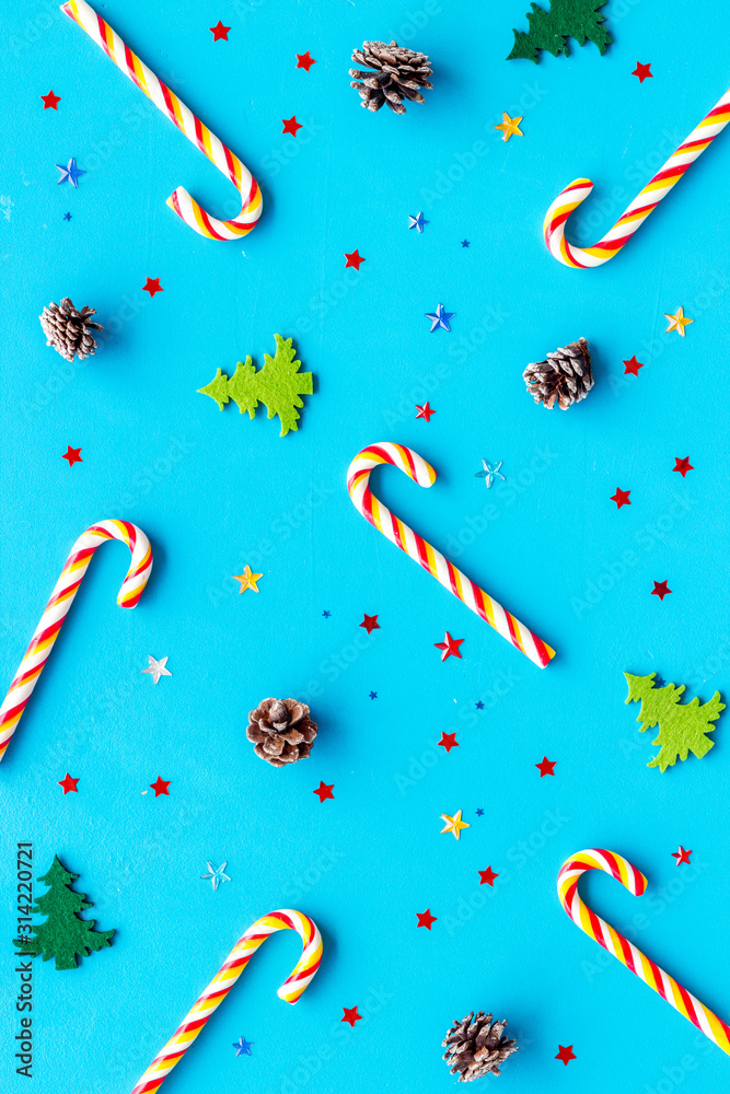 New Year background with Christmas candy cane, festive tree and balls. Pattern on blue desk top-down