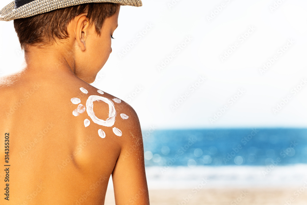 Child on the beach, sunscreen sun over shoulder