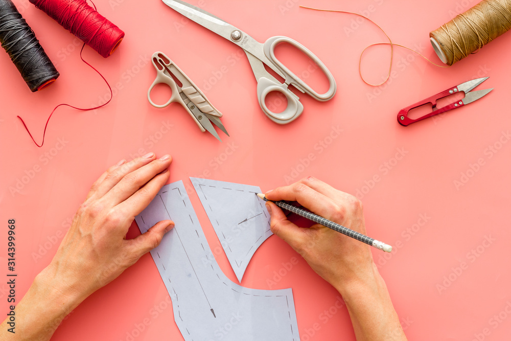 Tailor working. Women hands drawing patterns for clothes on pink background top-down