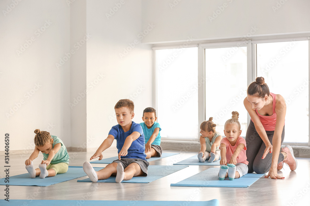 Little children practicing yoga with instructor in gym