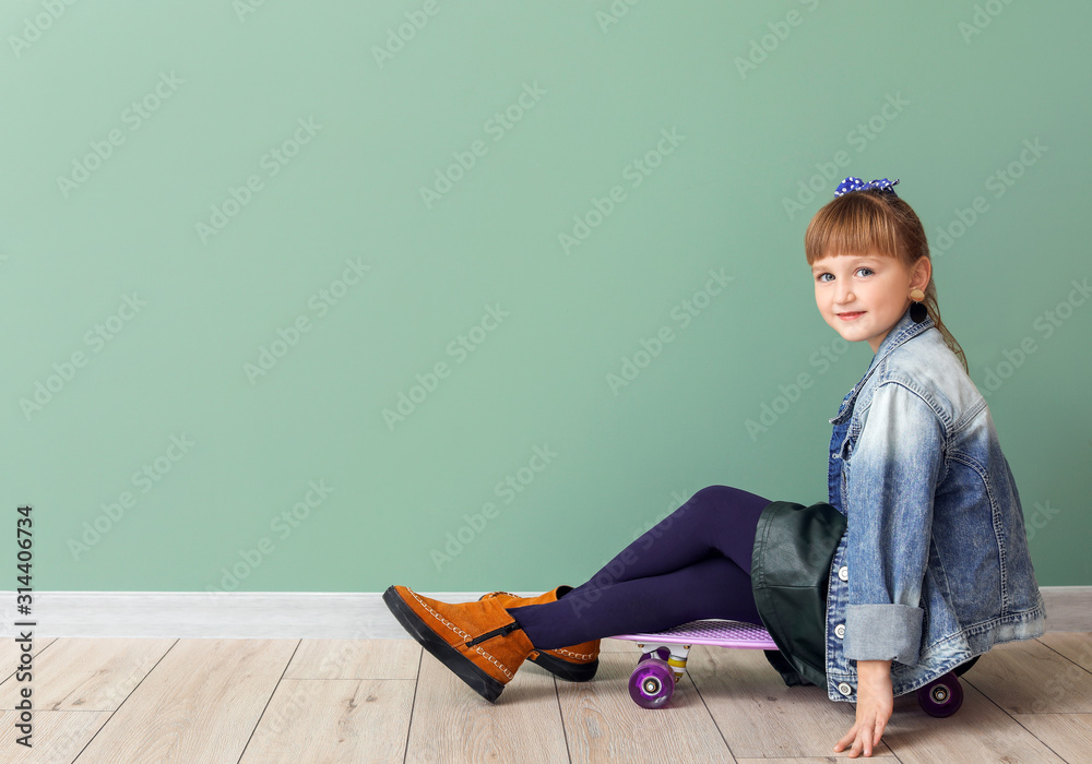 Cute fashionable girl with skateboard on color background