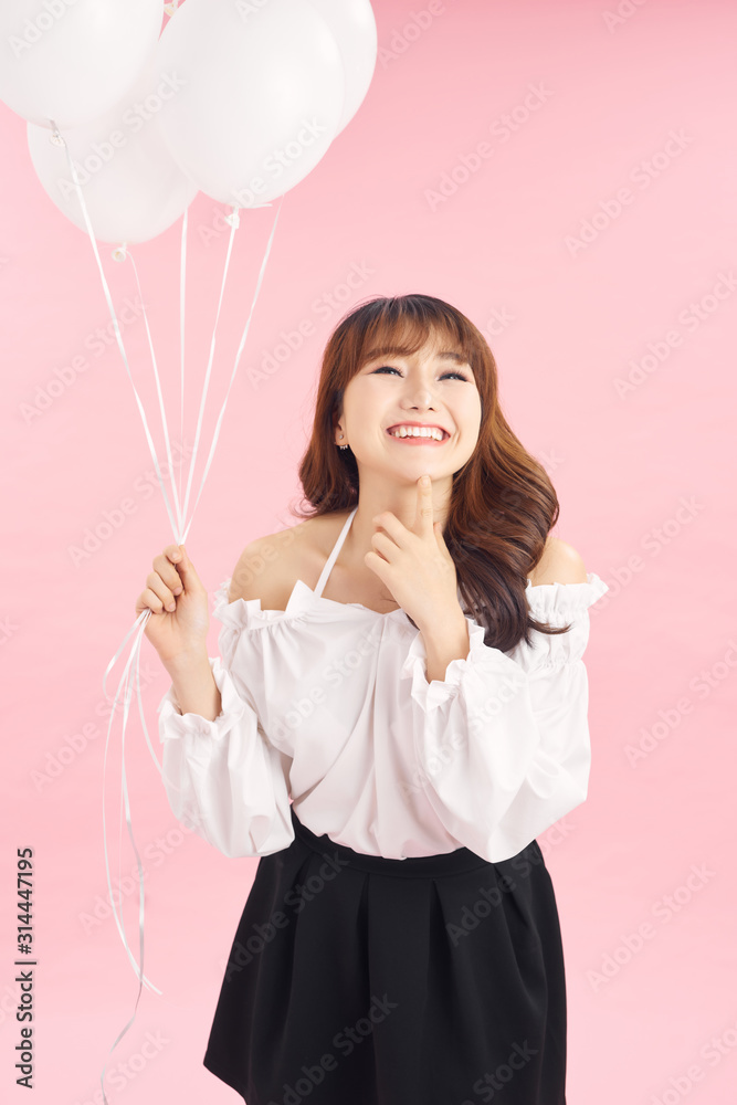 粉色背景下带着气球的微笑快乐女士的肖像。人物概念