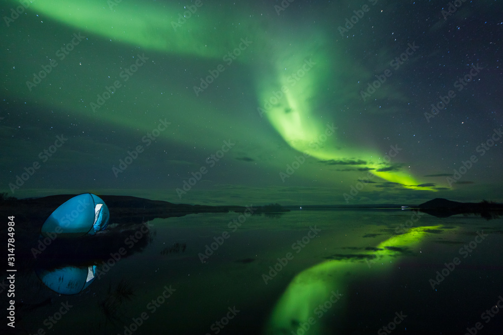 北极光（北极光）在湖边冰岛荒野的露营帐篷上方
