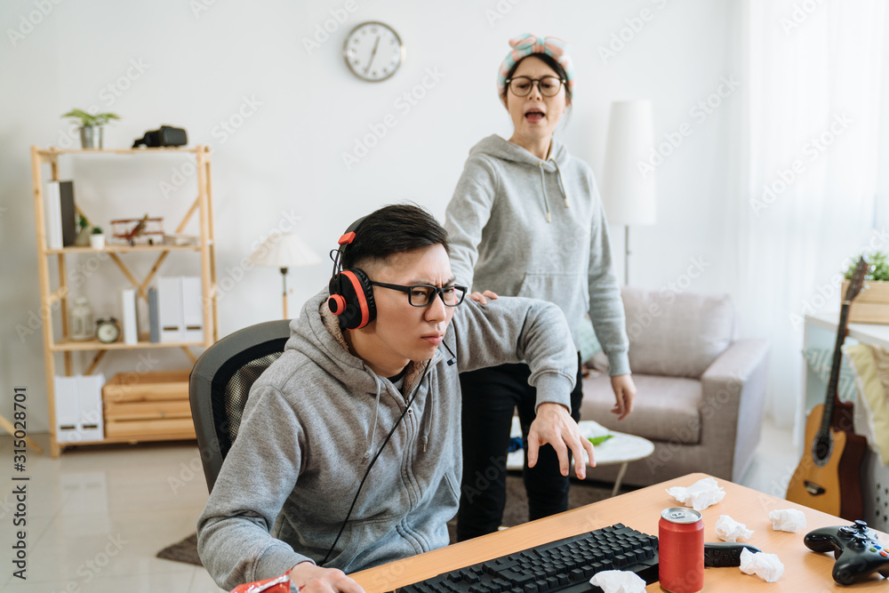 亚洲年轻女孩朋友对男朋友在电脑上玩网络游戏感到愤怒。疯狂的女人推着男人a