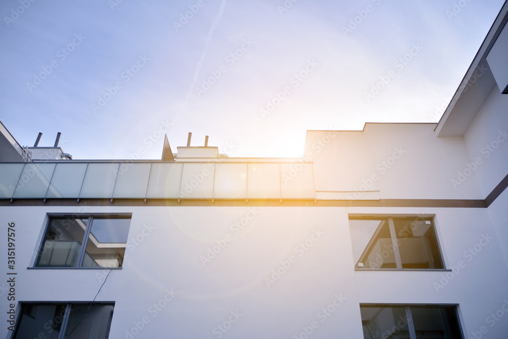 阳光明媚、天空湛蓝的现代公寓楼。现代公寓楼的立面。Gla