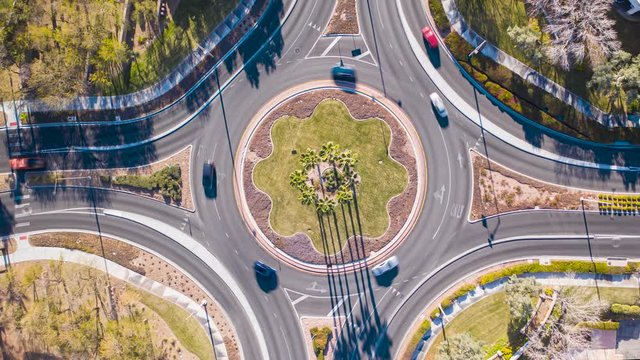 Aerial timelapse of cars driving in busy, pretty traffic circle roundabout 