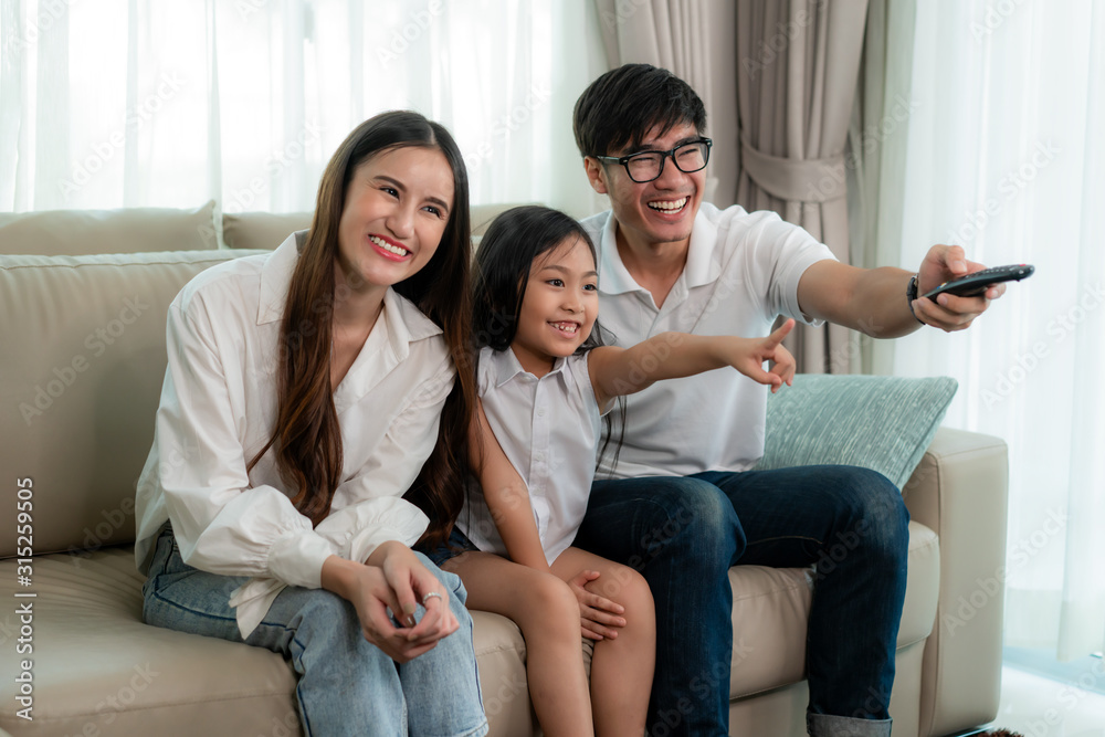 快乐的亚洲家庭成员在家看电视节目，享受周末活动。父亲，母亲a