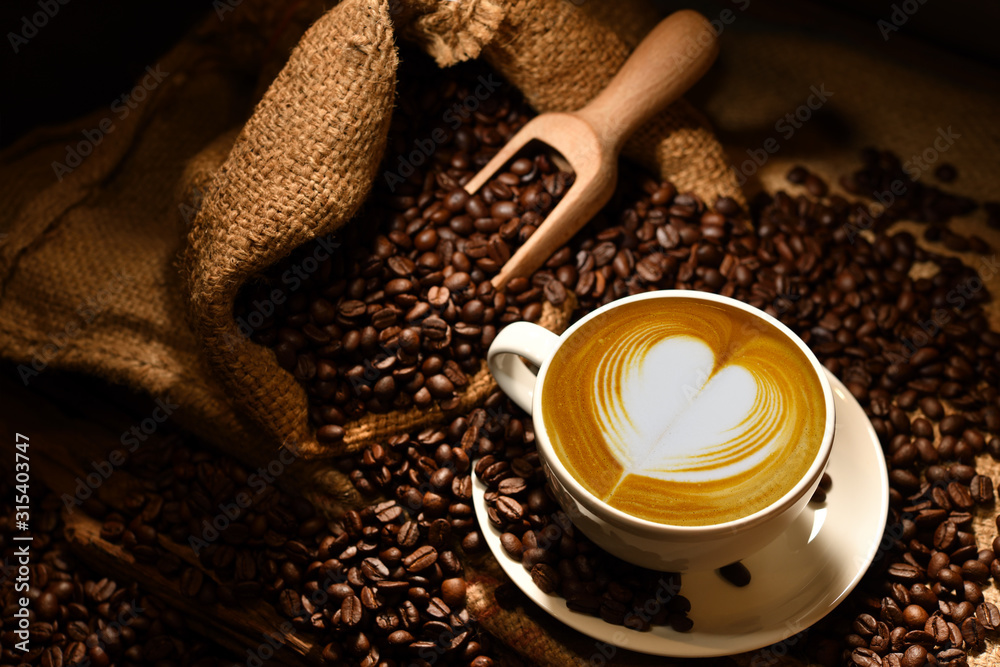 一杯心形咖啡拿铁，古老的木质背景上有咖啡豆