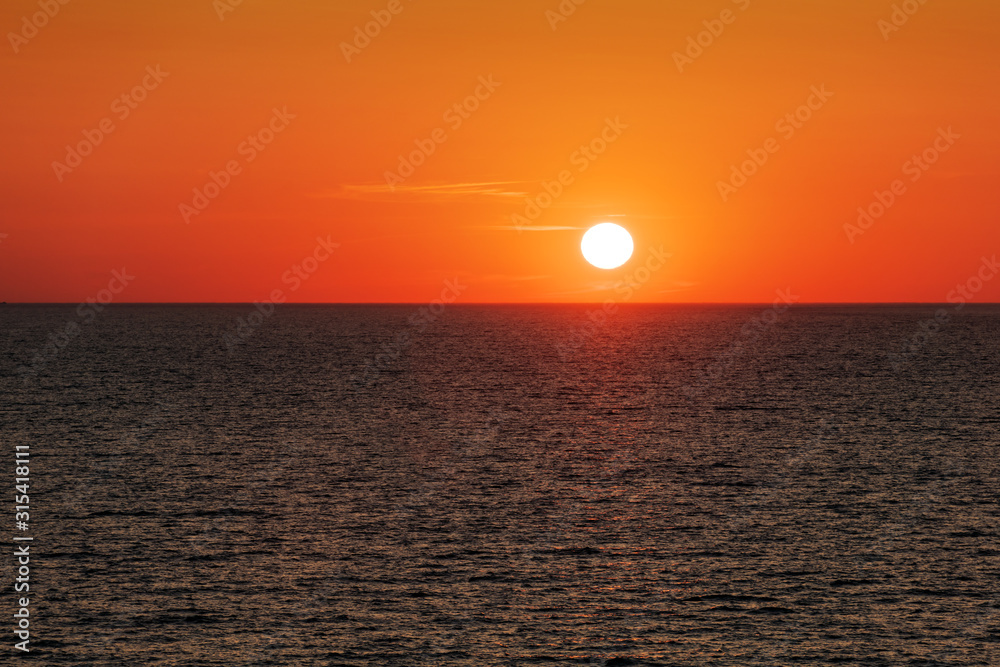 海洋中的日落，伴随着巨大的日暮柔和的海浪和红色多云的天空。海洋日出背景。陆地