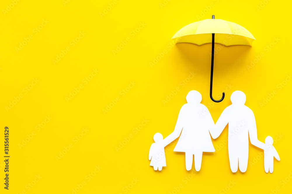 现场保险概念。黄色背景上有雨伞保护的家庭剪影自上而下复制