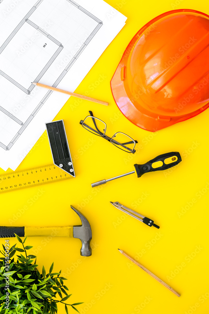 建筑工人工作台，带安全帽，黄色背景上的仪器和蓝图自上而下的框架副本