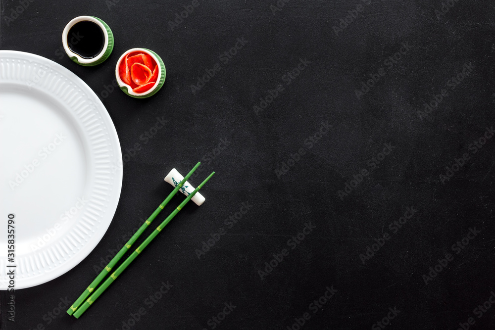 寿司和卷饼的餐具。盘子、筷子、小碗、姜和在黑底锅上煎