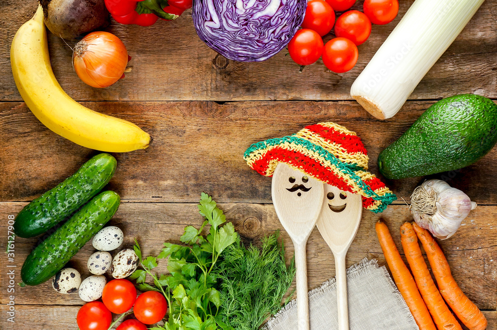 Fresh vegetables on wooden table with funny spoons with faces and summer hats