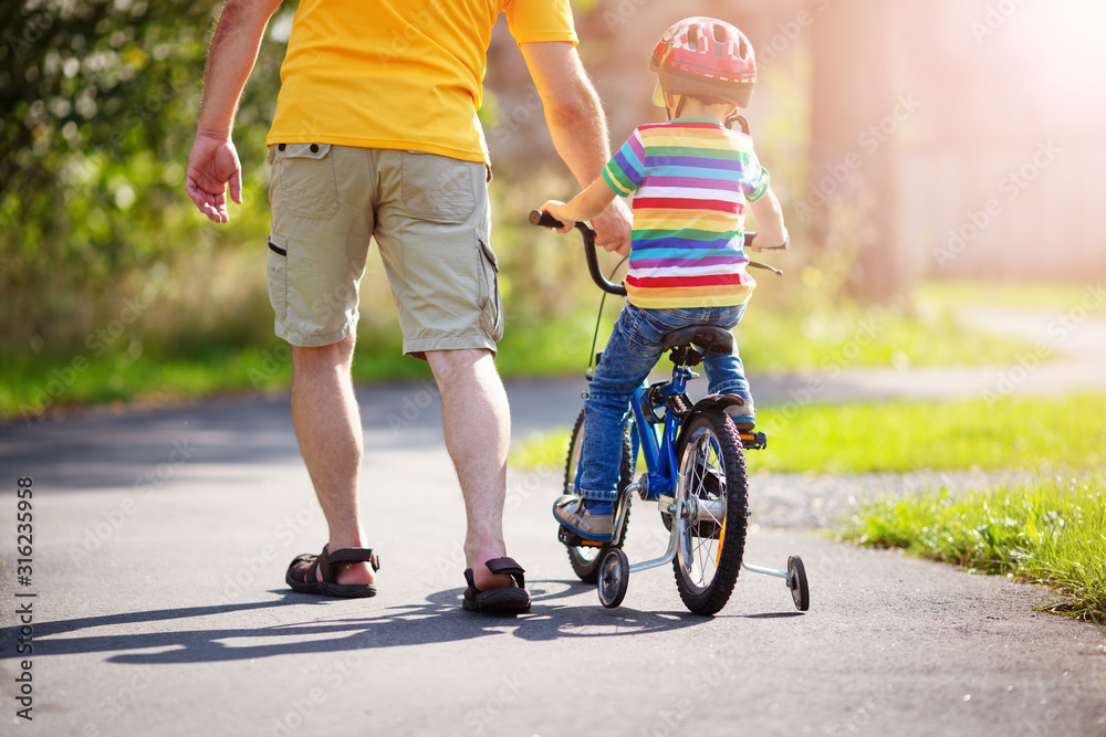 一个戴着头盔骑自行车的孩子和父亲在柏油路上