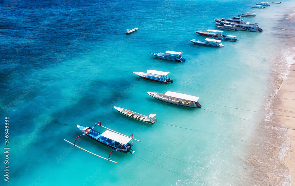 从俯视图看，水面和海滩上的船只。无人机拍摄的蓝色背景。夏日海景