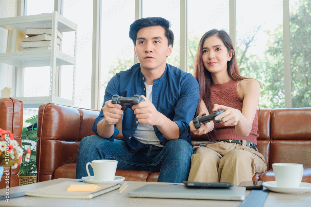 年轻夫妇在家玩电子游戏玩得很开心。