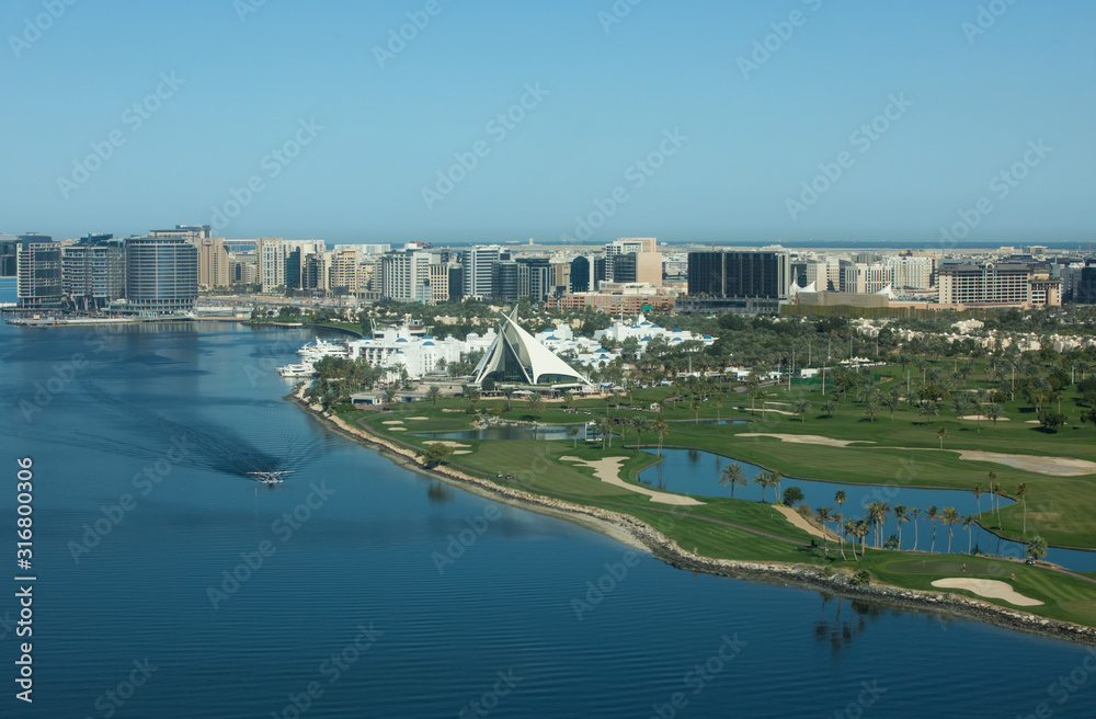 Aerial view of Dubai Creek, Creek golf greens, old Dubai and a sea plane on the water on a sunny day