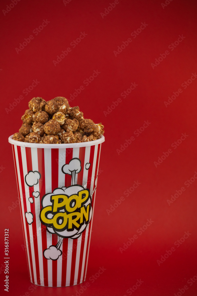 红色爆米花杯里的黄油爆米花巧克力，红底上的房子或电影院里的零食