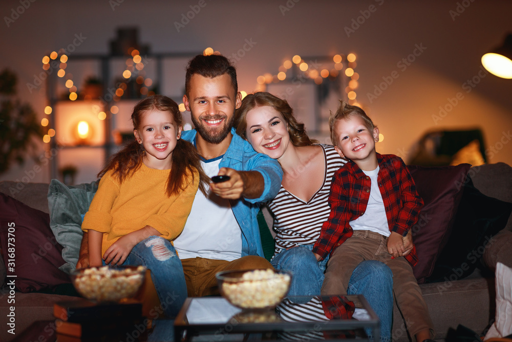 家庭母亲、父亲和孩子晚上在家里用爆米花看投影仪、电视、电影
