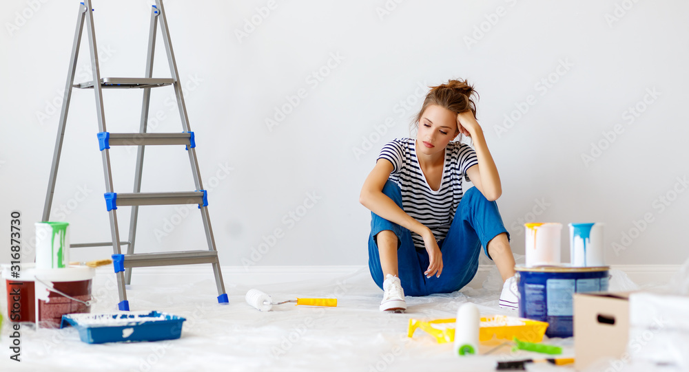 公寓里的维修。疲惫的年轻女子粉刷墙壁。