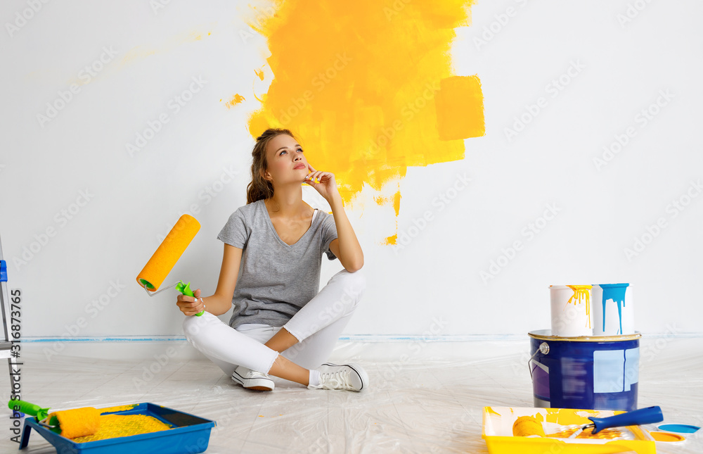 公寓维修。快乐的年轻女人粉刷墙壁。