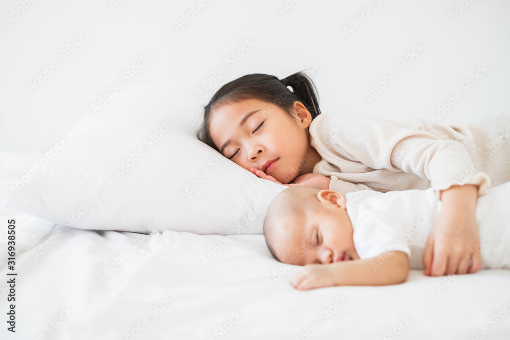 Asian cute girl sleep with baby on white bed