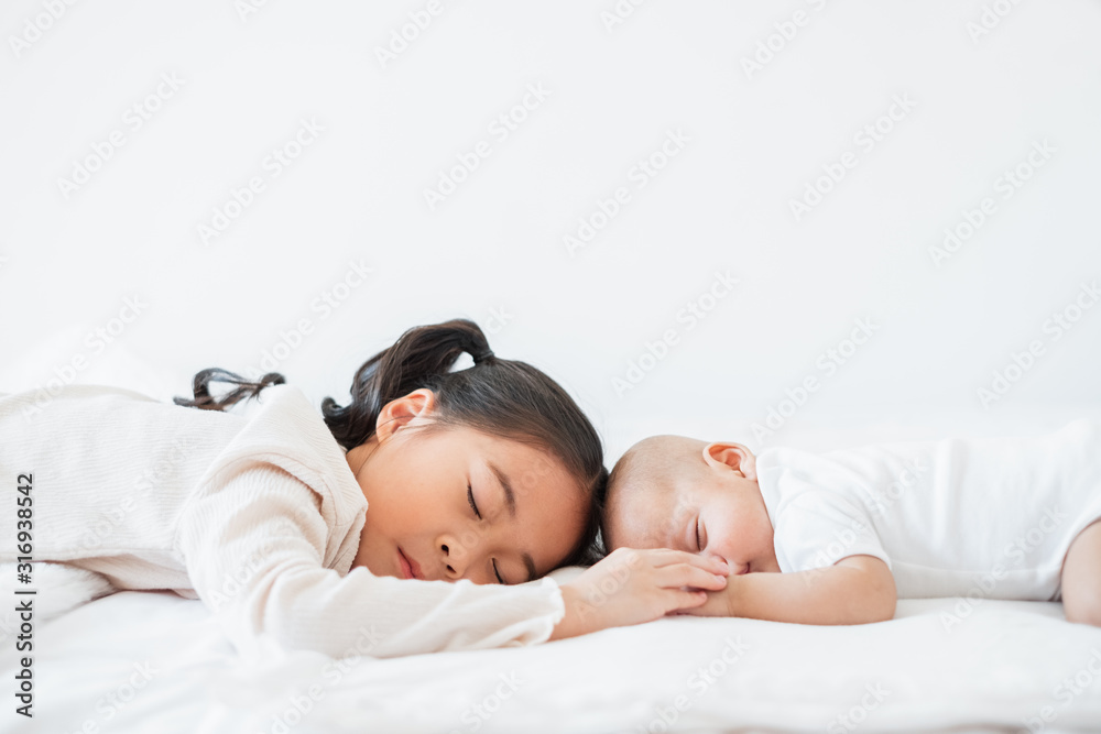 亚洲可爱女孩与婴儿睡在白色床上