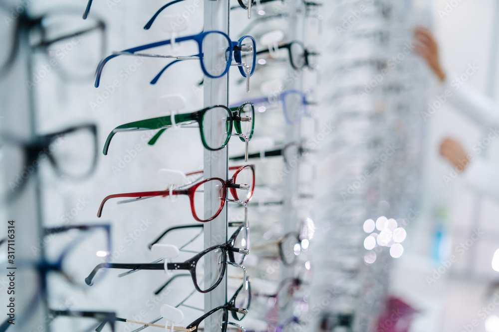 带着眼镜站在眼镜店里。女人的手会选择眼镜。