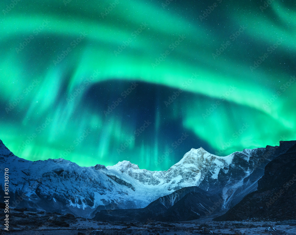Aurora borealis above the snow covered mountain peak in Norway. Northern lights in winter. Night lan