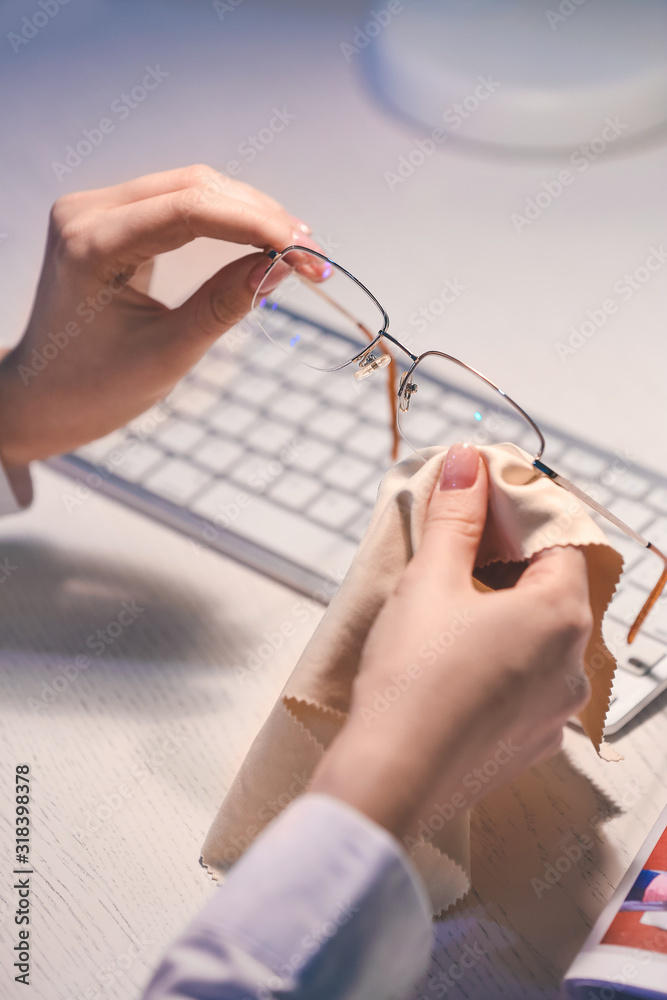 年轻女子在桌子旁擦眼镜，特写镜头