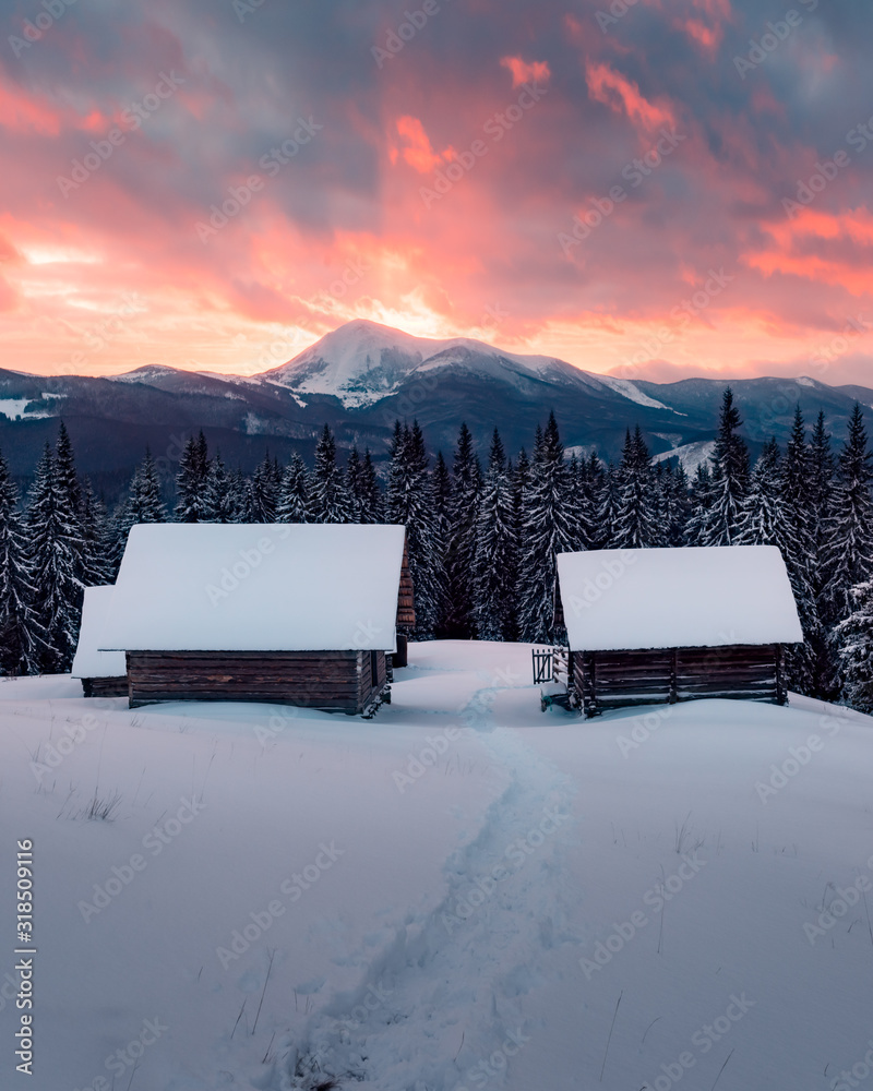 雪山中木屋的奇妙冬季景观。雾蒙蒙的阳光下高耸的山峰