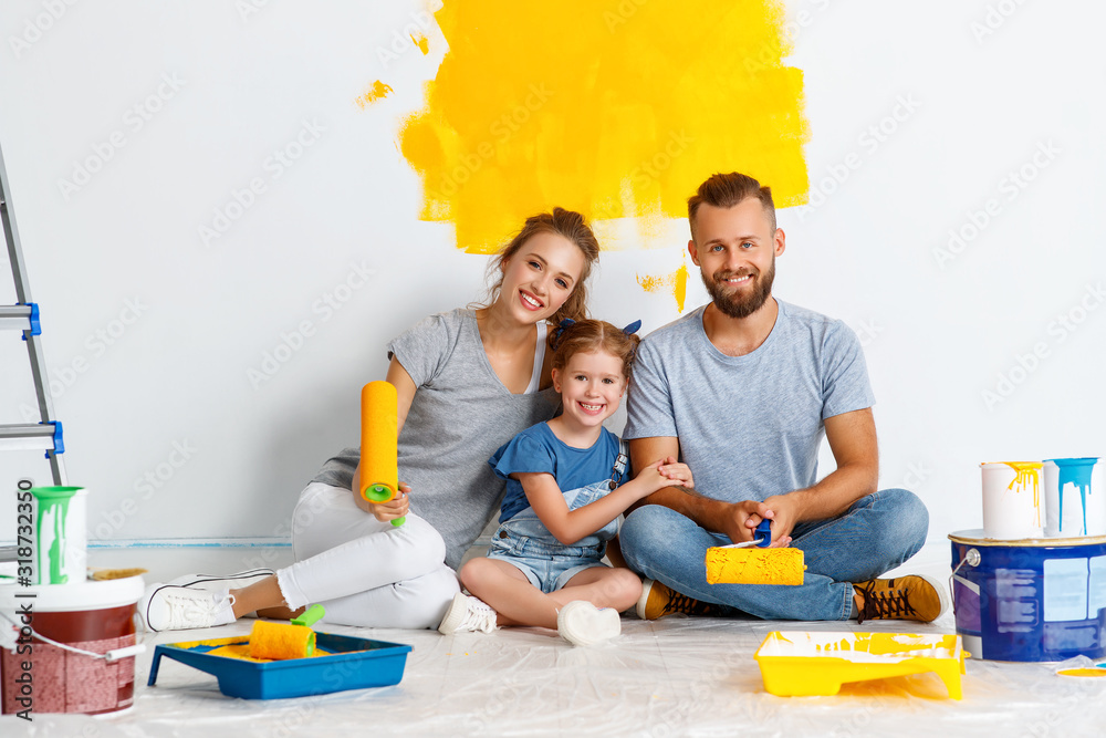 在公寓里维修。幸福的家庭母亲、父亲和孩子的女儿在墙上画画。