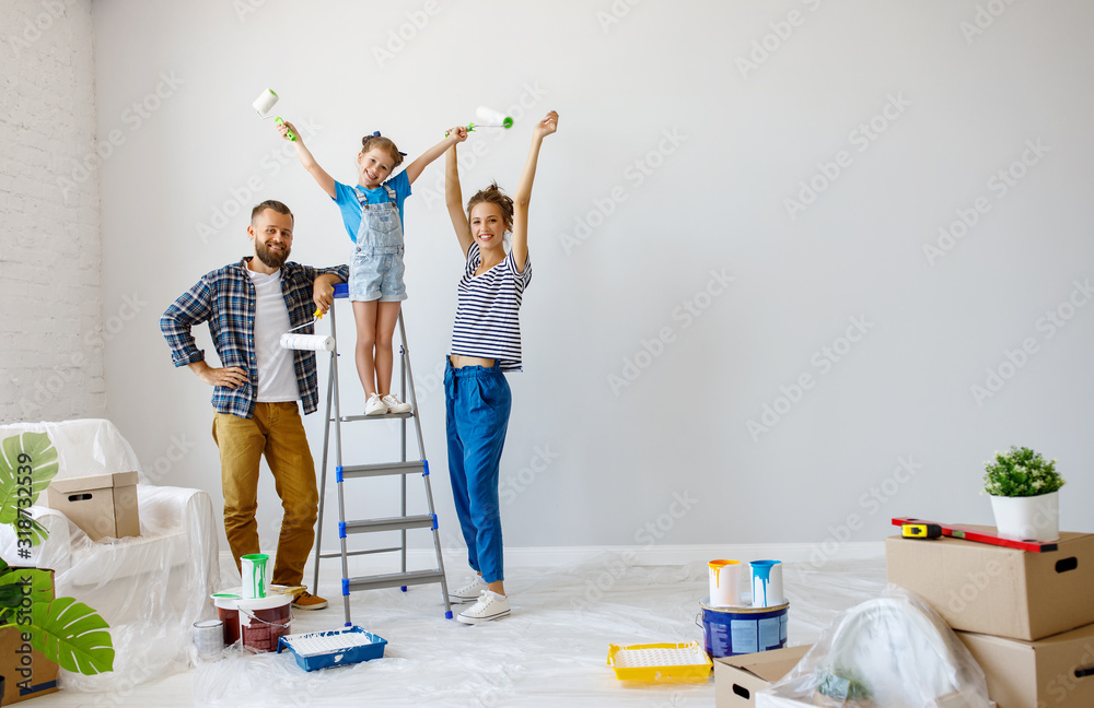 在公寓里维修。幸福的家庭母亲，父亲和孩子的女儿粉刷墙壁。