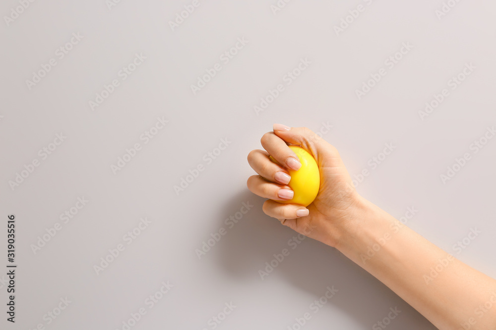 Hand squeezing stress ball on light background