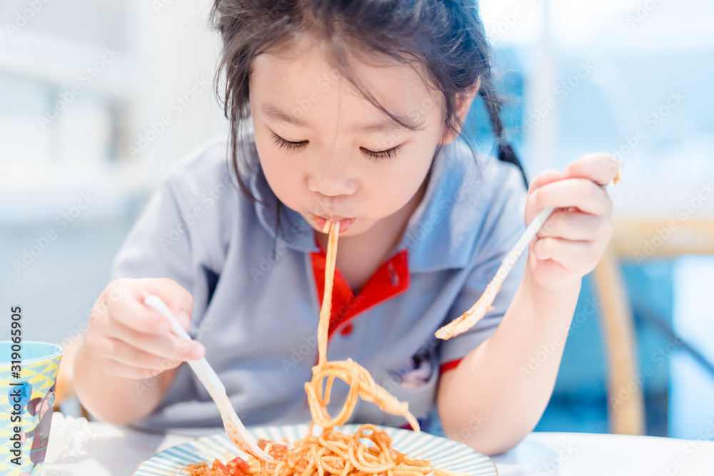 饥饿的脸和享受饮食的概念。亚洲小女孩喜欢吃意大利肉酱和奶酪。