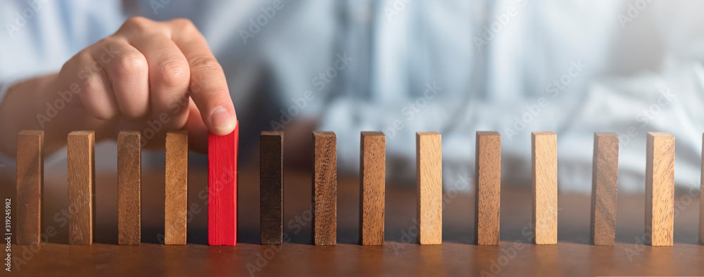商务人士尝试在木桌上选择红色木块和深色背景商务组织sta