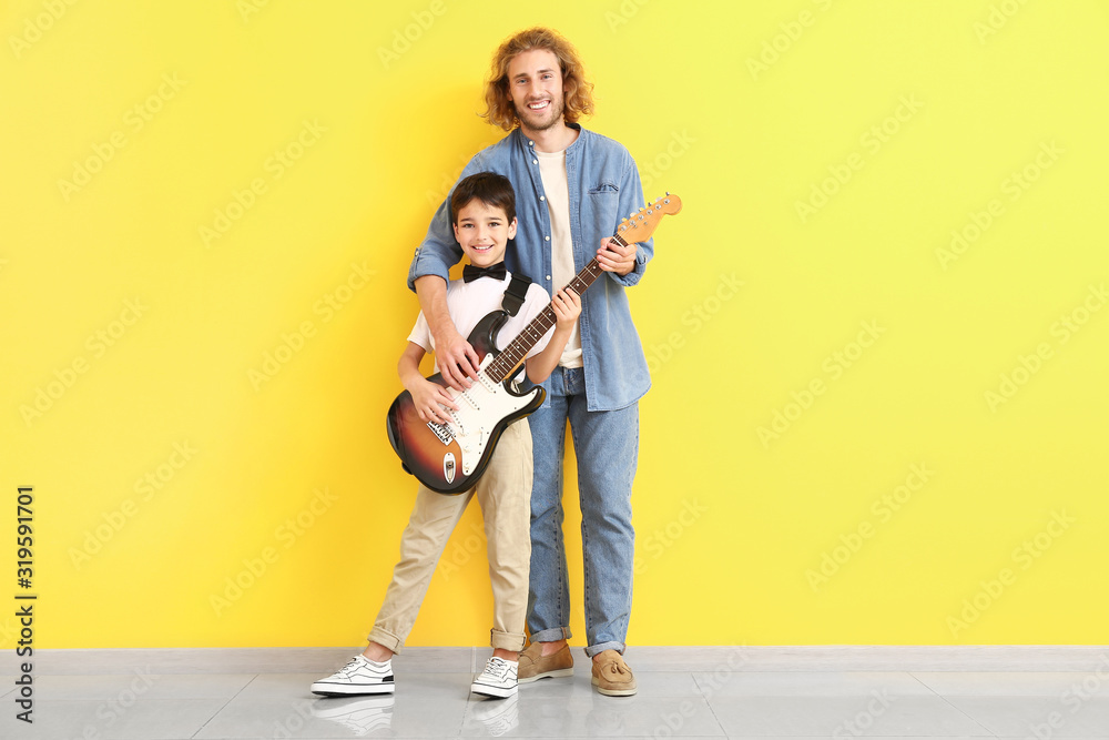 一个男人和他的小儿子在彩色墙附近拿着吉他